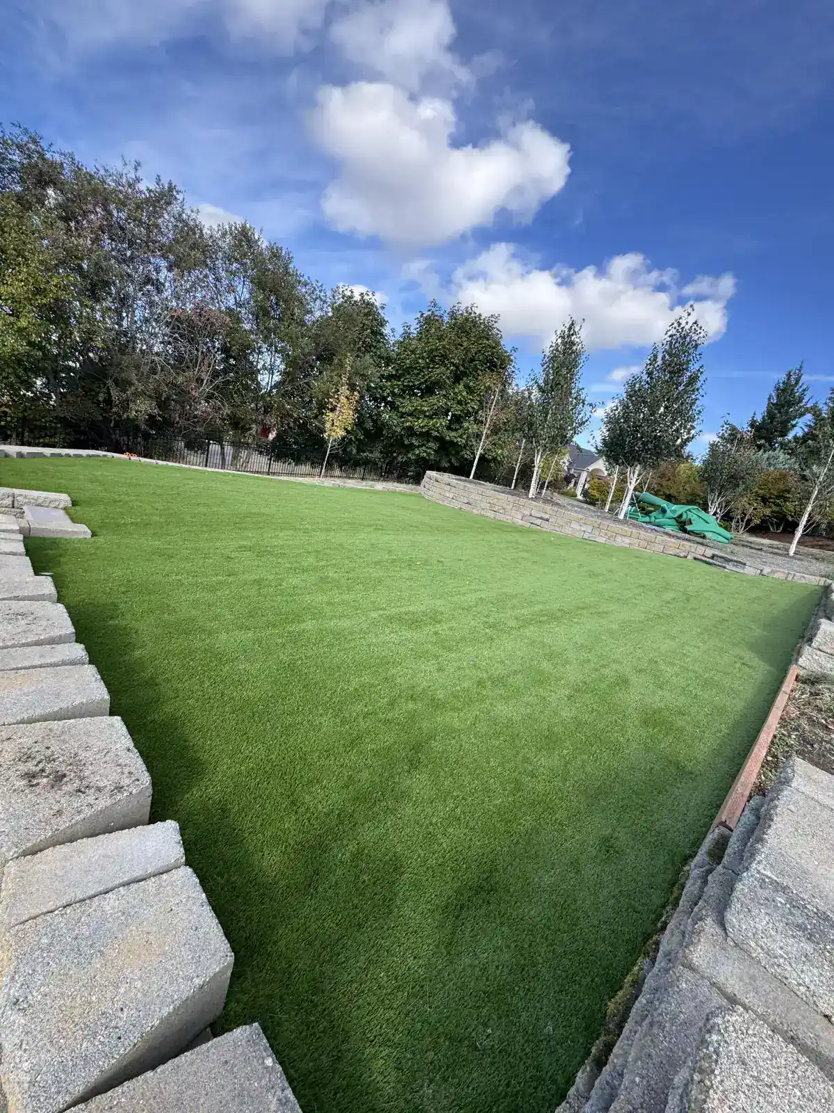 Large luxury backyard with artificial turf paver patio and retaining wall by CreekView Landscape in Oregon
